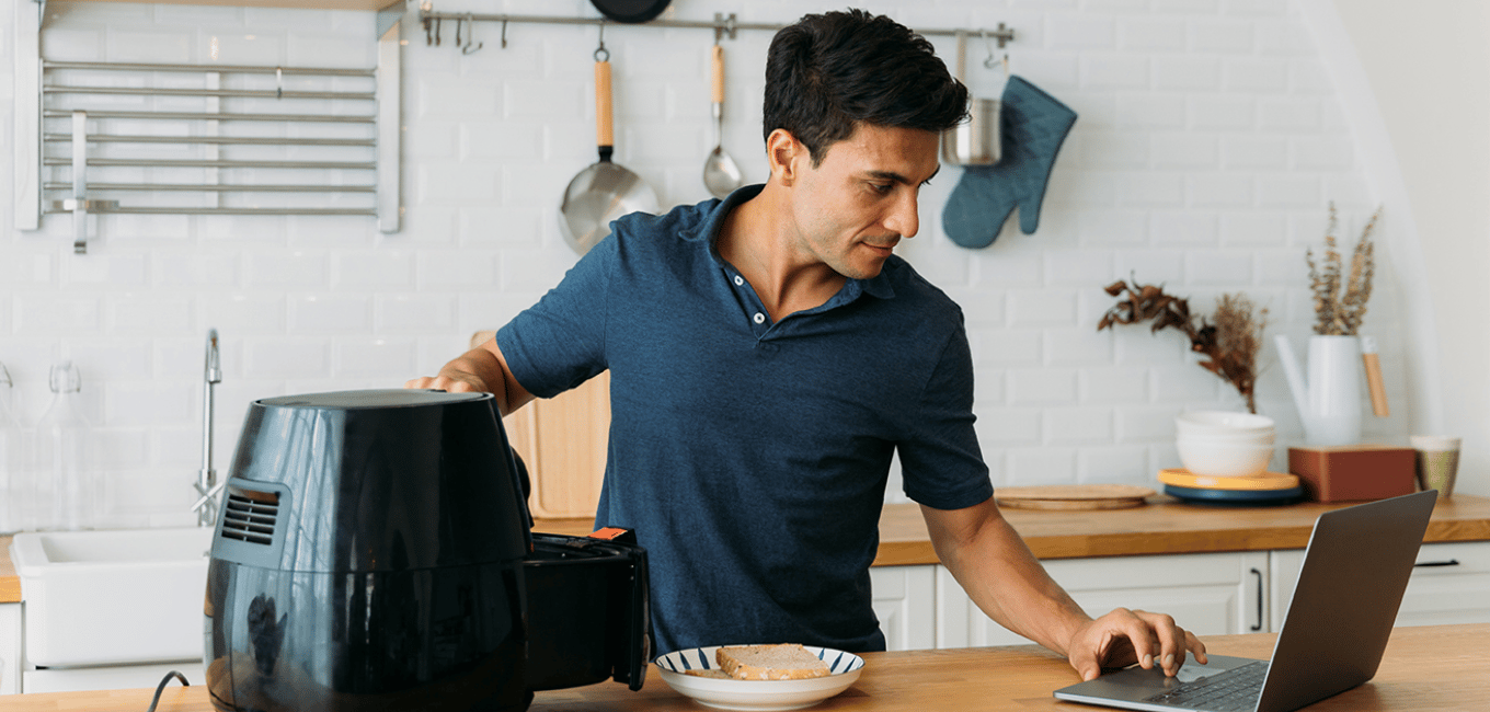 man using laptop while cooking in an air fryer (1)